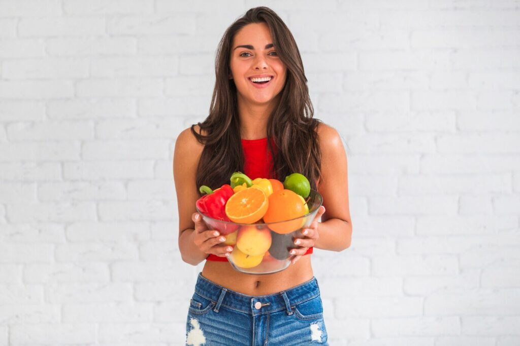young woman holding bowl of fresh vegetables and fruits to Boost Your Immune System Naturally.