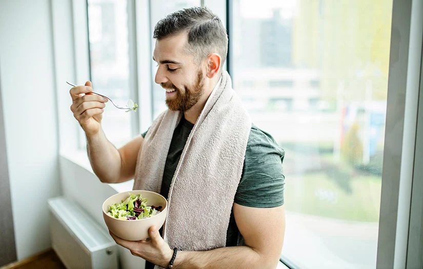 man eating best superfoods after exercise and smiling while eating.