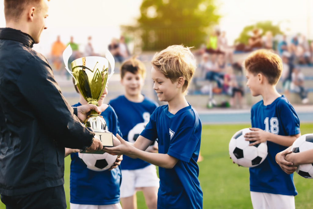 This image shows the man giving trophy to kids.