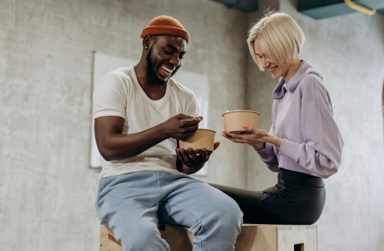 Two friends sharing a joyful moment while enjoying a healthy meal indoors.