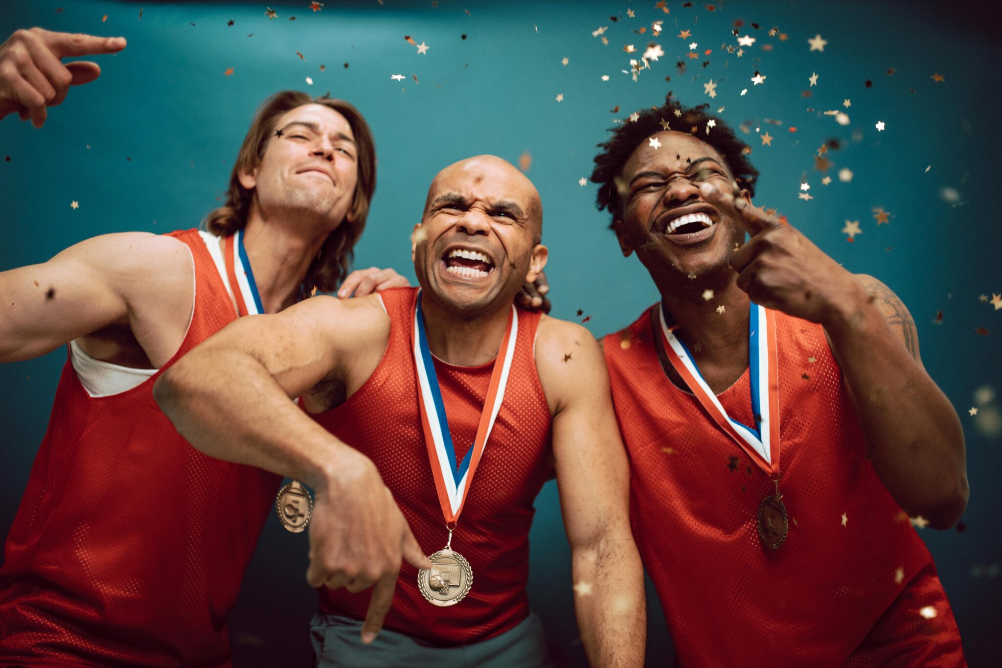 Three diverse athletes celebrate their victory with medals and confetti, best sports documentaries