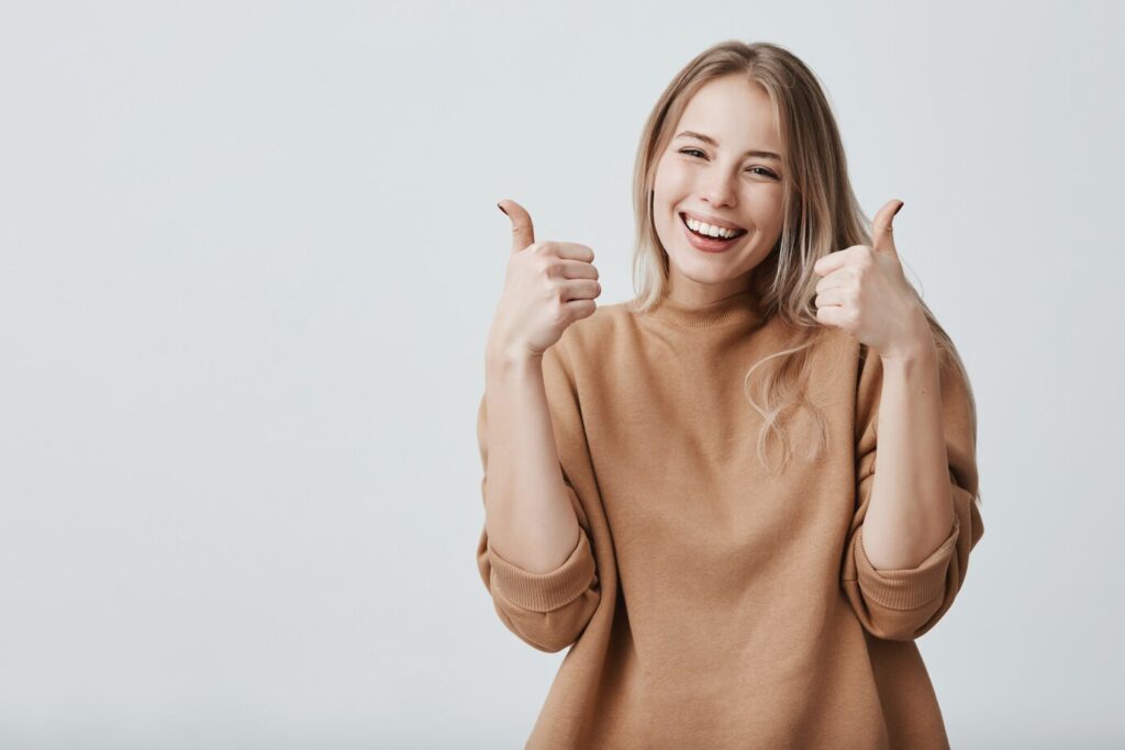 portrait-fair-haired-beautiful-female-woman-with-broad-smile-thumbs-up