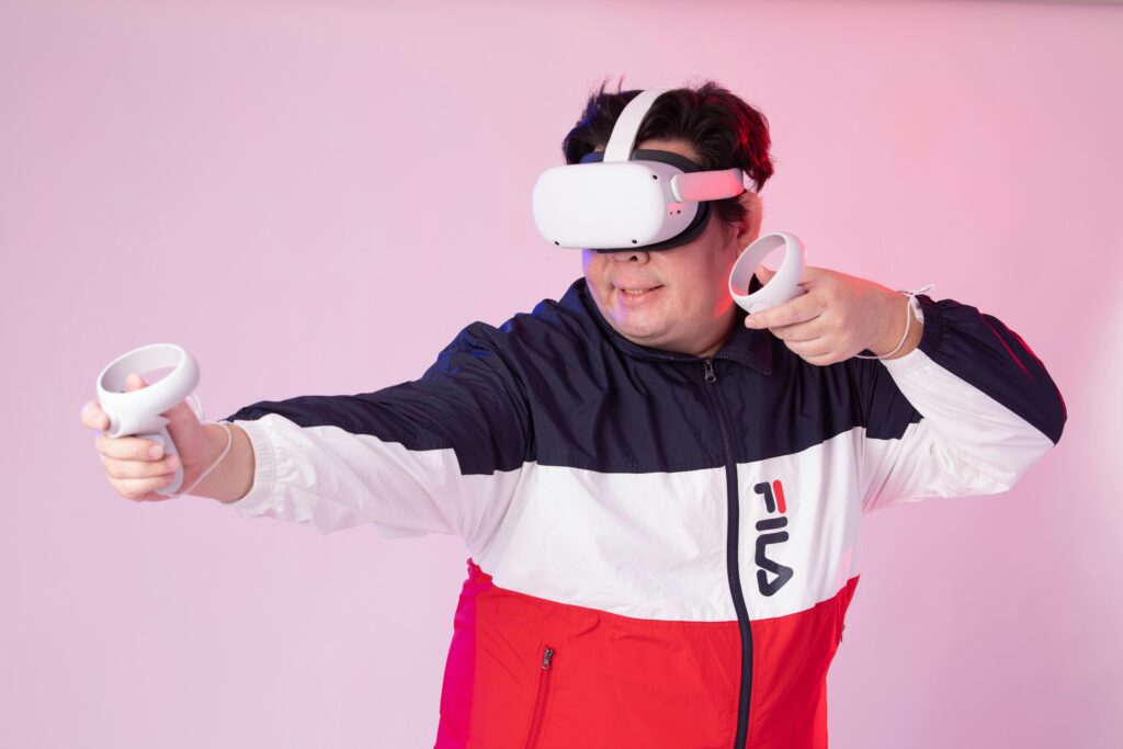 Young male enjoying a virtual reality game using VR headset and controllers in a studio setting.