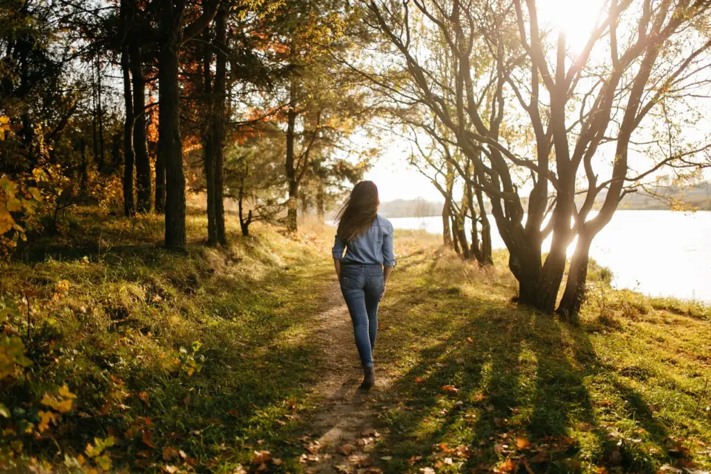 Woman walking in the green grass with sunshine. 