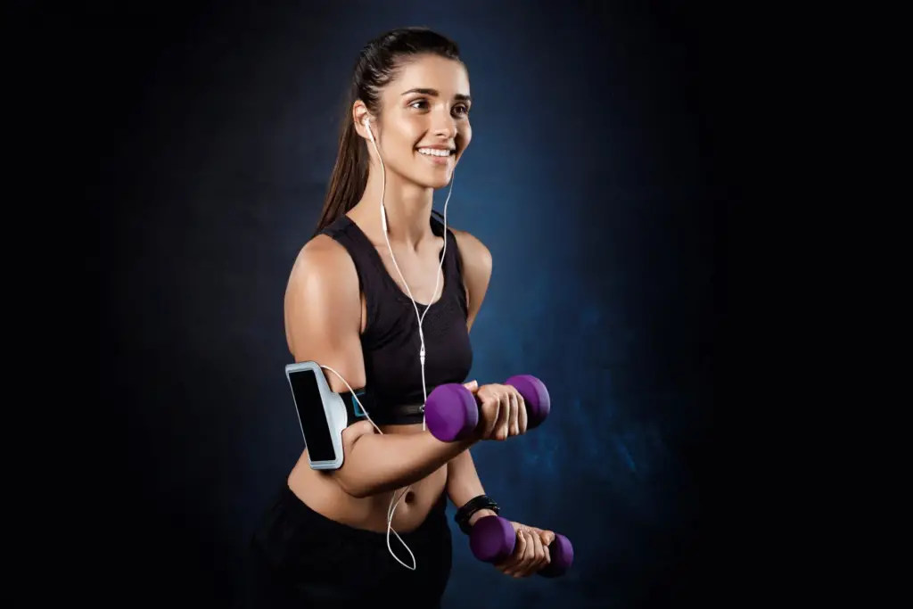 This image shows the young woman smiling and doing weightlifting.