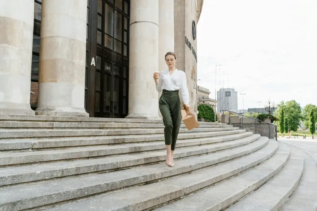 Fashionably dressed woman walking down steps with coffee and paper bag