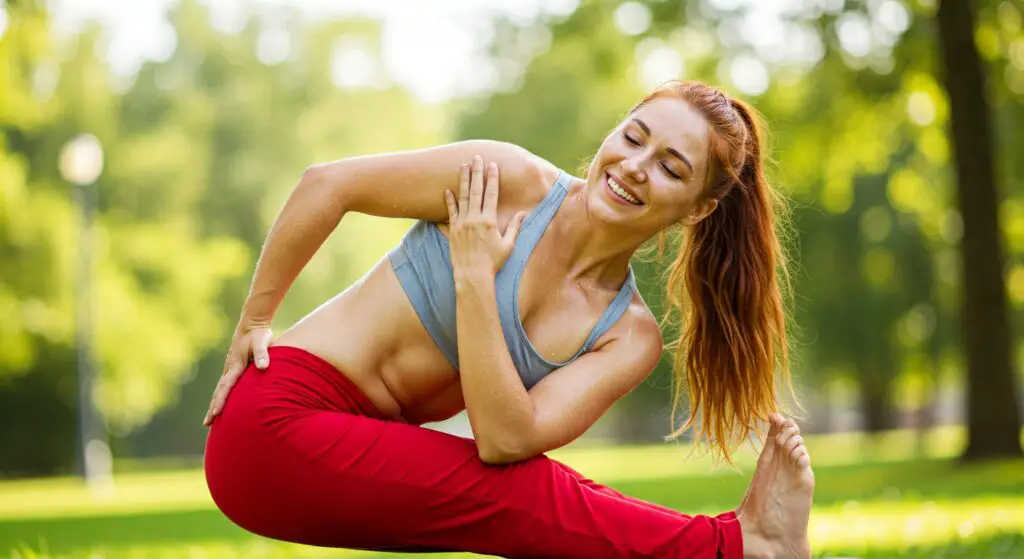 woman doing outdoor hot yoga sweating exercise and smiling.