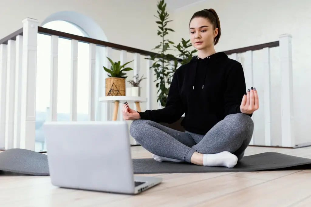 Woman performing desk yoga in the yoga mat while working.