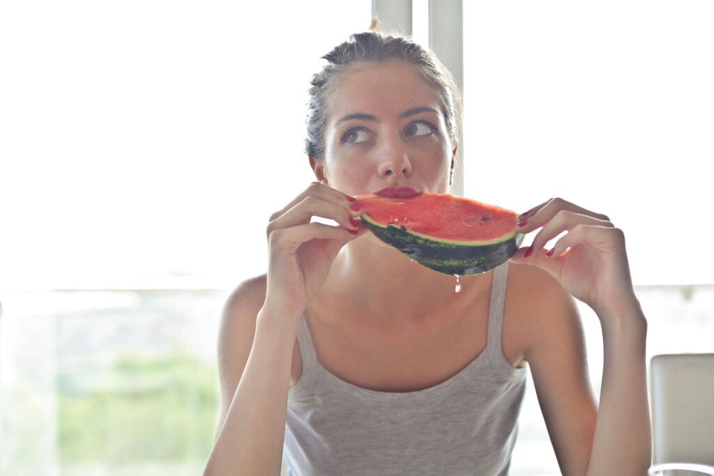 Portrait of a pretty woman eating watermelon indoors, reflecting health and summer vibes, water-rich fruits