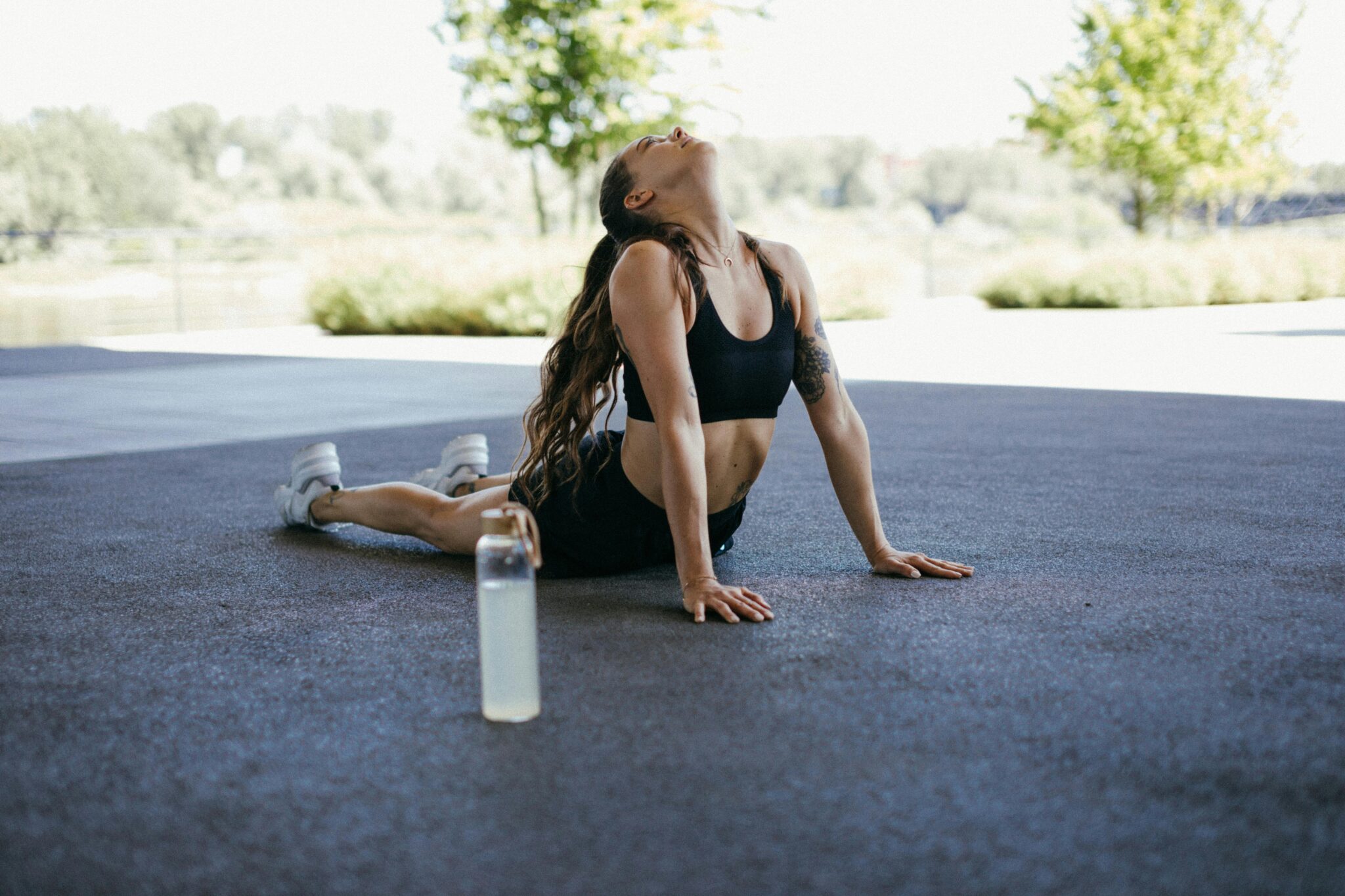 Fit woman doing yoga stretch outdoors, promoting fitness and wellness.